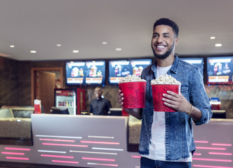 Mozambican model holds two popcorn packets, at the Gloria Mall cinema in Maputo, for the  Millennium BIM 2019 campaign, Dobra Mola. 
