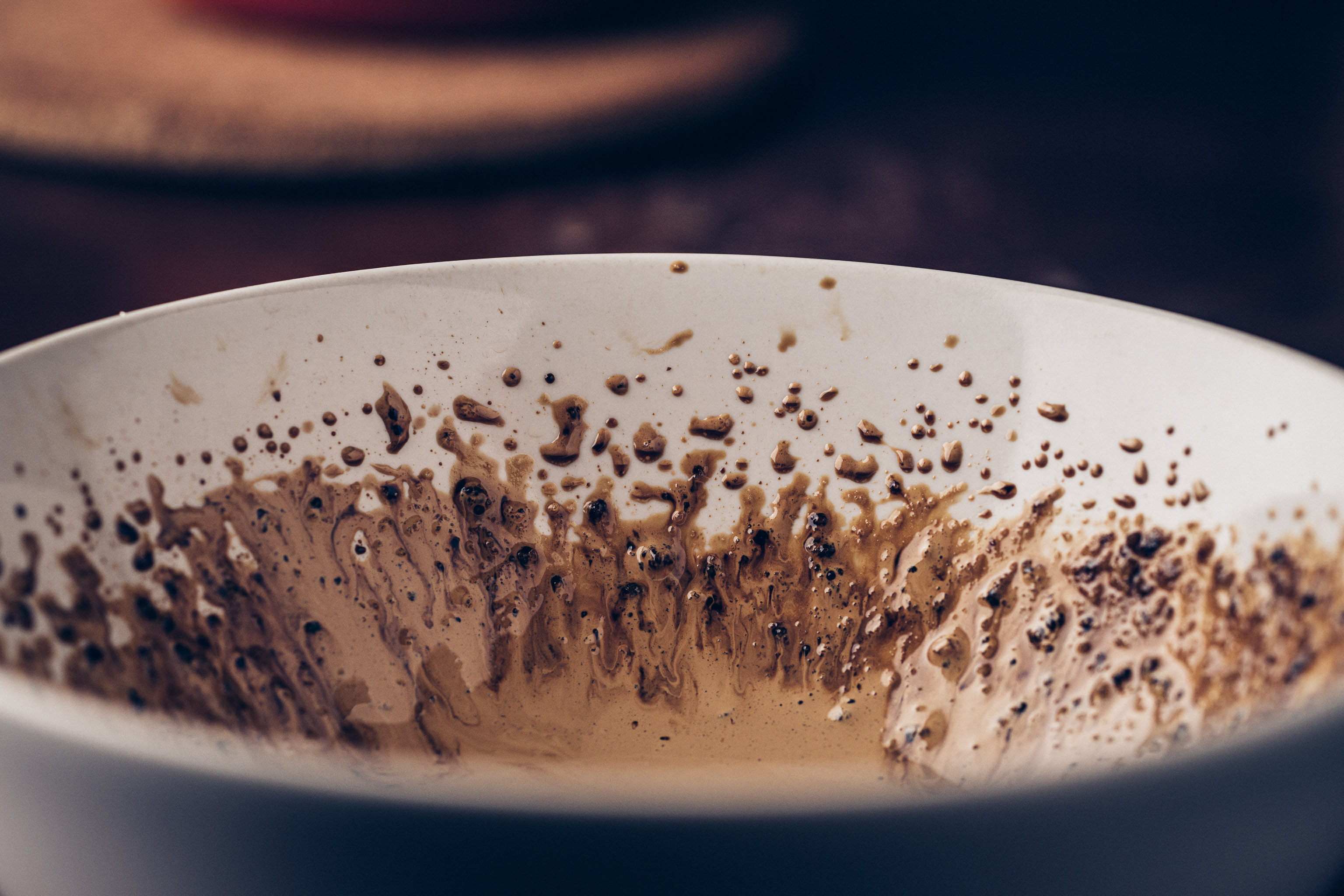 Close-up of the inside of a mixing bowl, splattered with whipped dalgona coffee residue.
